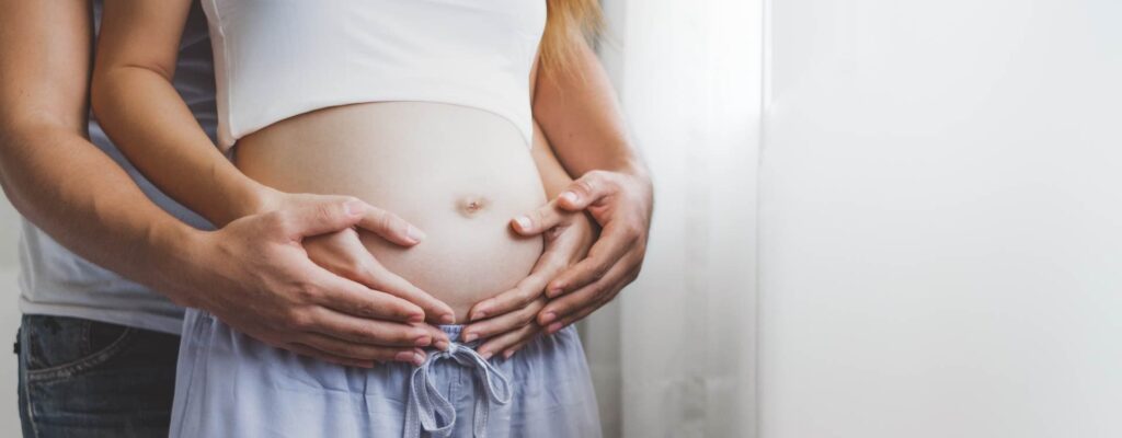 Couple holding pregnant wife's stomach.