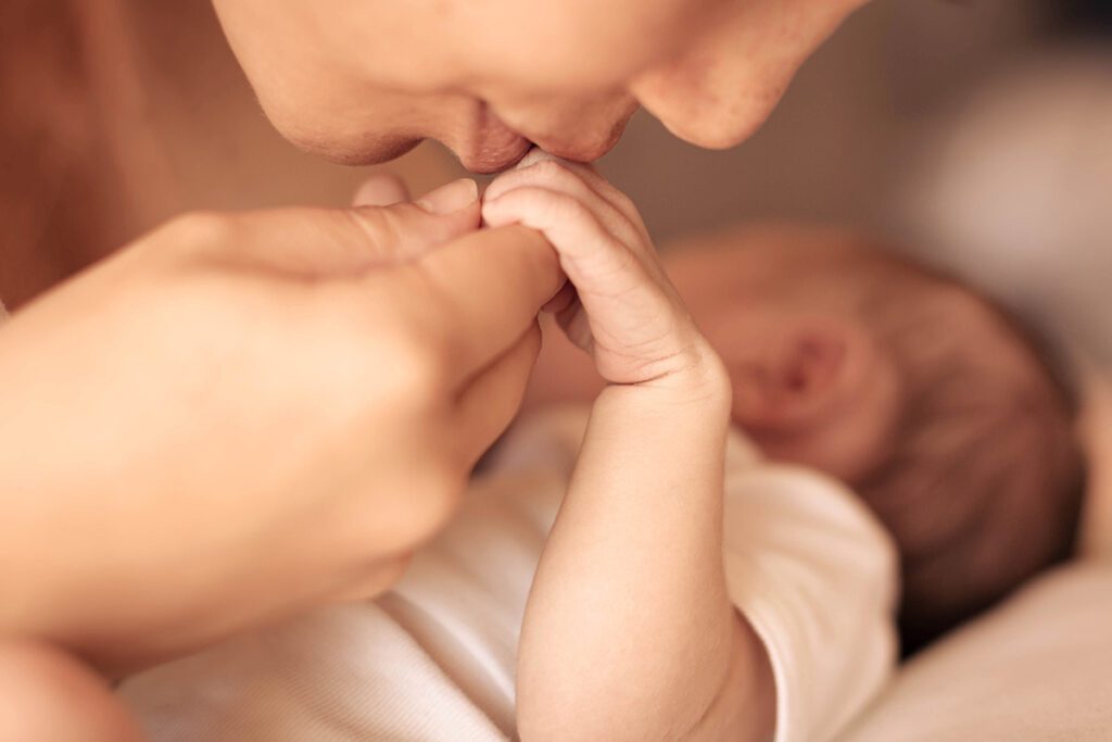 Mother Kissing Newborn Babys Hand After Cord Tissue Banking